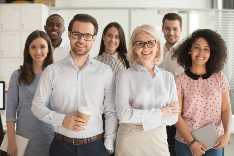 Mitarbeiter stehen in einem modernen Büro und posieren gemeinsam für ein Gruppenfoto.